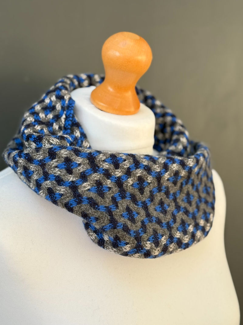 Thumbnail: navy and grey mosaic patterned snood scarf on a mannequin against a dark grey wall