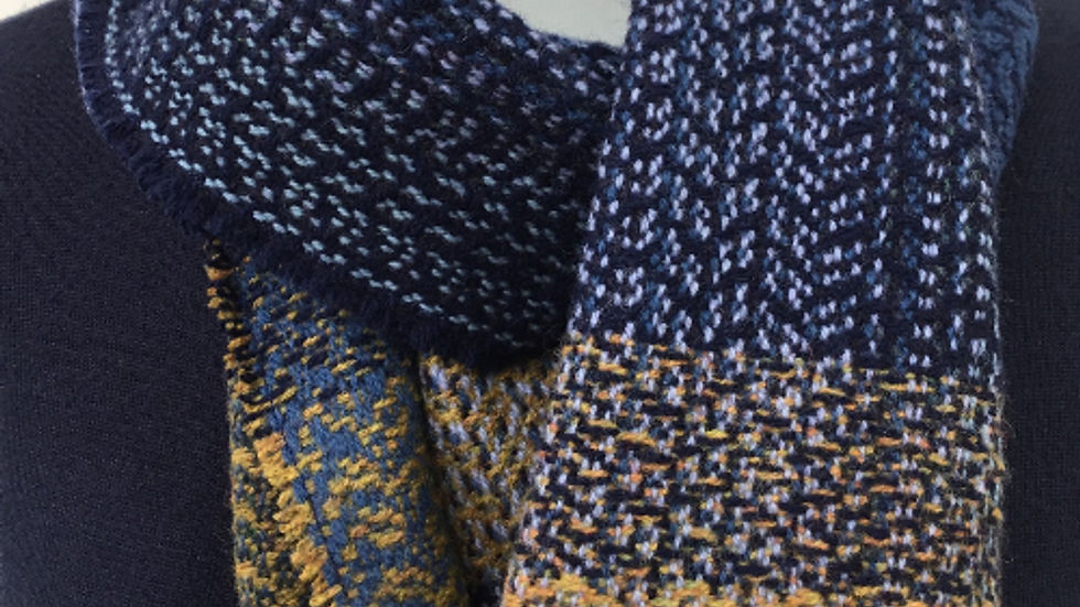 A navy and yellow woven scarf with a textured pattern is draped around the neck of a mannequin in a neutral setting.