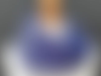 Purple and gray patterned scarf on a mannequin with wooden top. Neutral background. No visible text or emotions.