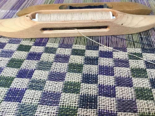 Thumbnail: Purple and ecru merino lambswool being handwoven in doubleweave on a floor loom — made by Emma Baker in Salisbury, Wiltshire