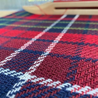 Tartan weaving on the loom with shuttles at the back