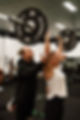 Personal Trainer spotting someone performing an exercise in the gym.