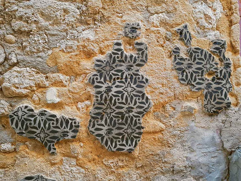 Spraypainted stencil on patches of plaster forming island-like shapes on a cracked historic wall, Favara, Sicily