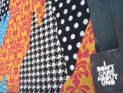 Close-up of the mural showing the overlap of three patterns: white polka dots on black, black and white houndstooth, and an orange damask pattern with hidden silhouettes.