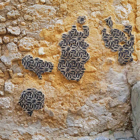 Spraypainted stencil on patches of plaster forming island-like shapes on a cracked historic wall, Favara, Sicily