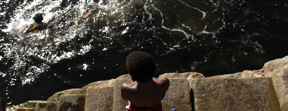 Crianças brincam e nadam na baia de Guanabara apesar da poluição