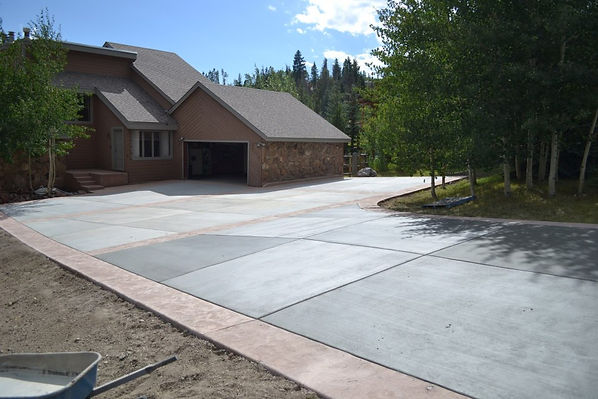 A large and long concrete driveway leading into a Colorado mountain home.