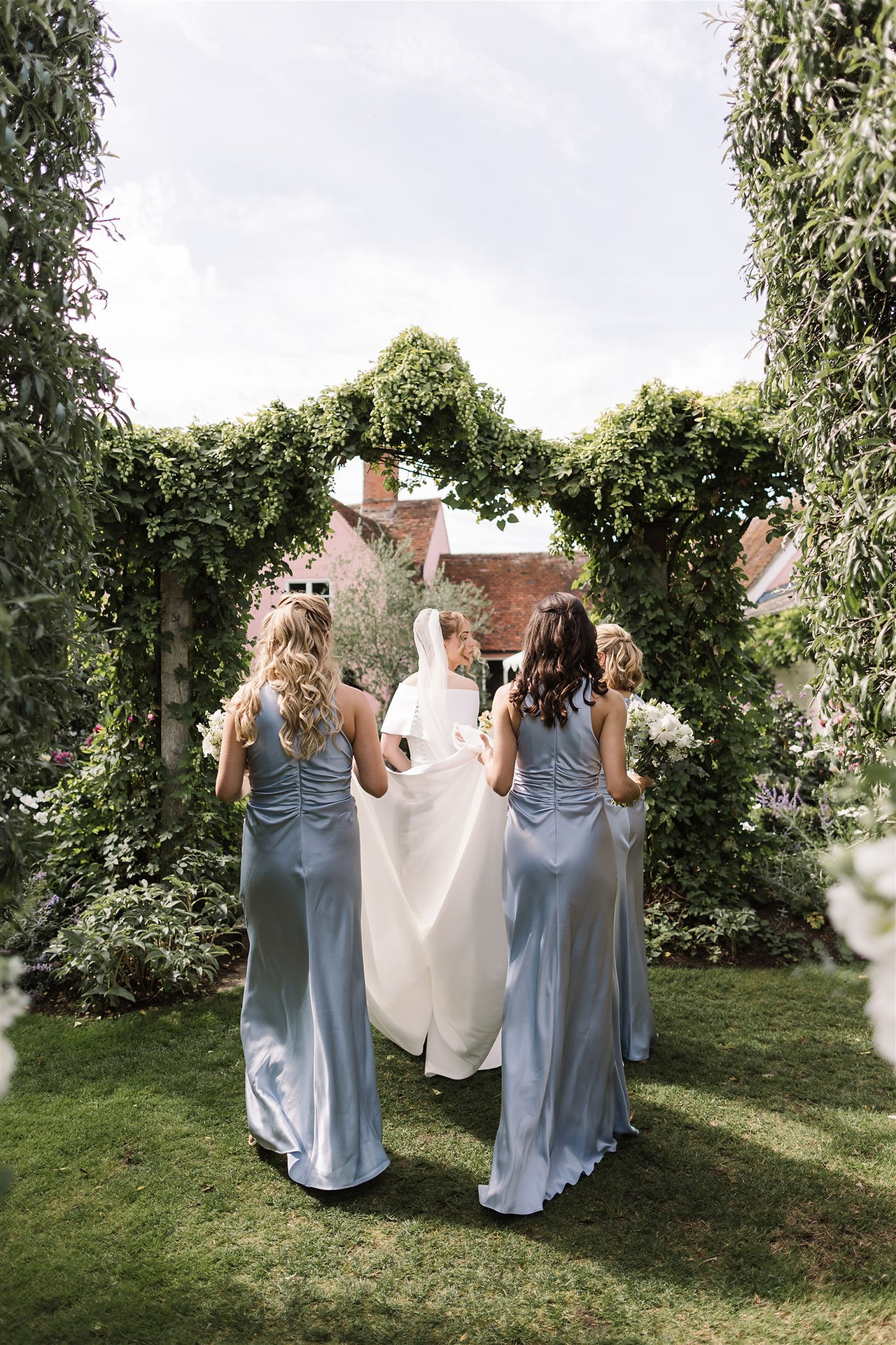 bridesmaids holding brides dress as she walks