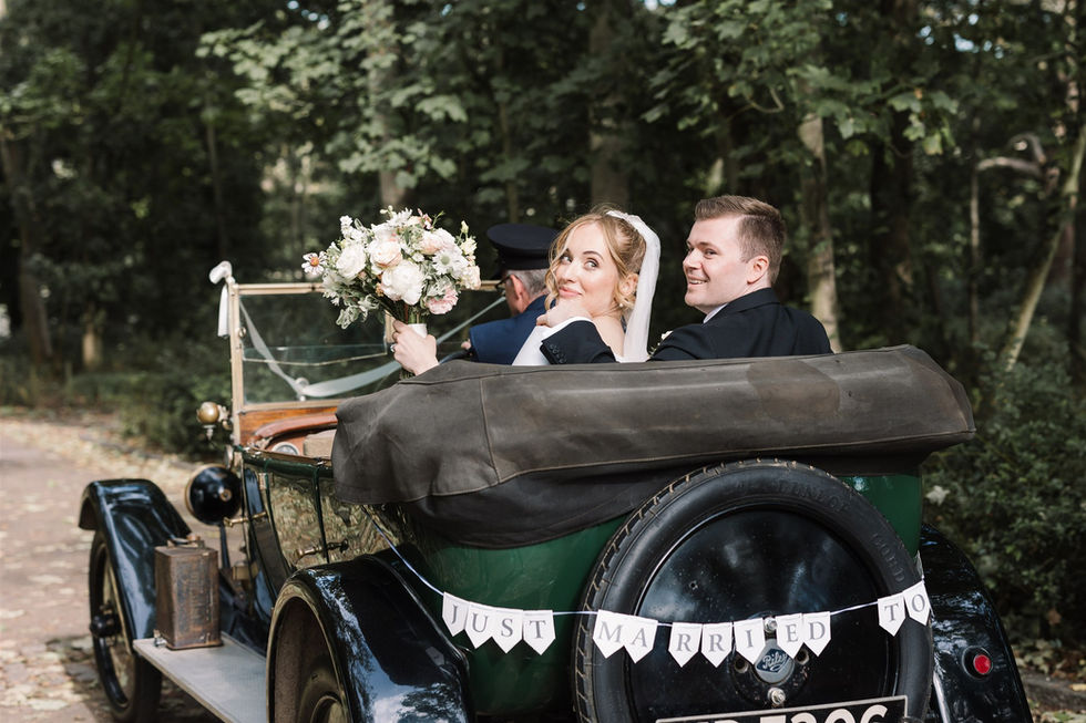bride and groom in open top wedding car