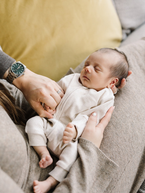 parents hands holding newborn baby