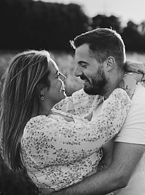 Schwarz-Weiß-Porträt eines Paares, das sich lächelnd in die Augen blickt – emotionale und intime Momentaufnahme.