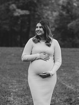 Schwarz-Weiß-Porträt einer schwangeren Frau, die lächelnd ihren Babybauch hält – natürliche, liebevolle Schwangerschaftsfotog