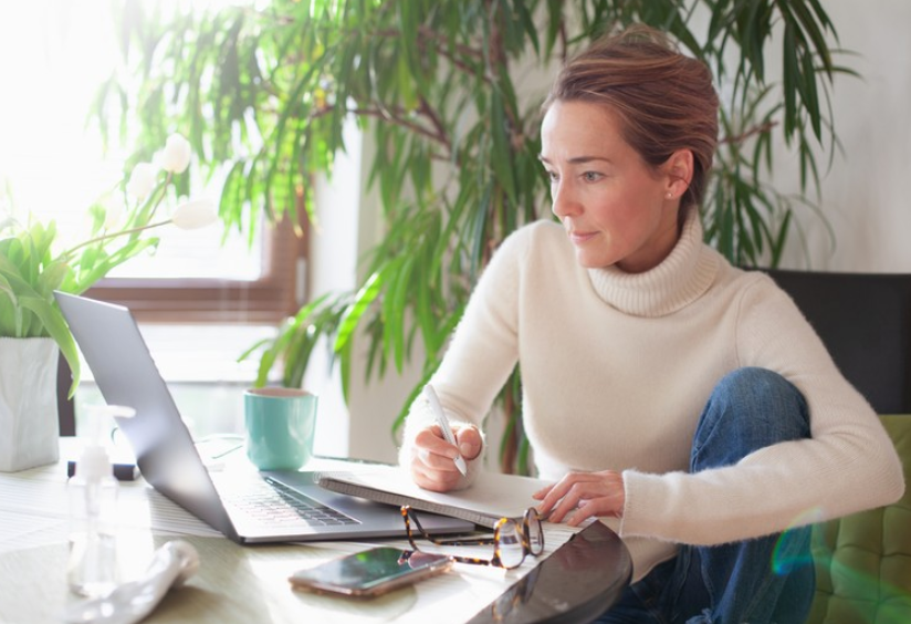 woman writing next to laptop