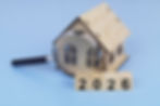 A close-up view through a magnifying glass of a small wooden house model with the year '2026' in the foreground, symbolising the detailed expert analysis of the Reading housing market provided by Beechwood Mortgages.
