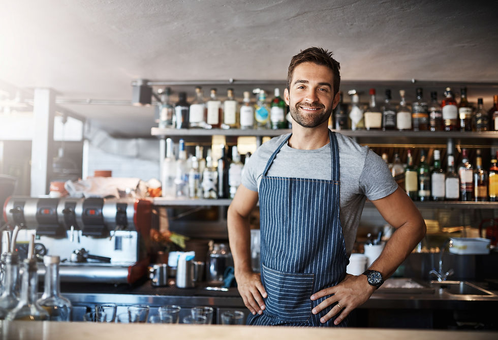 A confident bartender stands proudly inside his bar, symbolising his achievement of securing a mortgage as a self-employed individual through expert broker guidance.