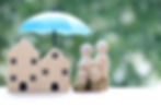 A model family standing under a protective blue umbrella that covers a pile of gold coins, symbolising the mortgage protection and financial security provided by Beechwood Mortgages in Reading.
