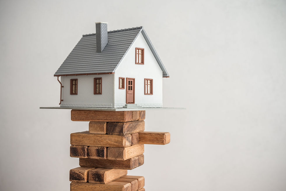 A model holiday let property perched on a pile of building blocks, with one block slightly pulled out, symbolising the importance of thorough research to ensure a stable and successful investment.