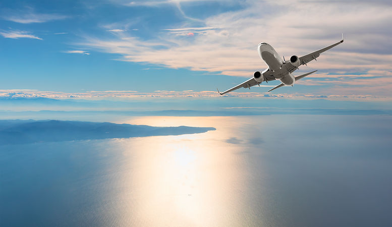 Airplane flying over tropical sea at sunset.jpg