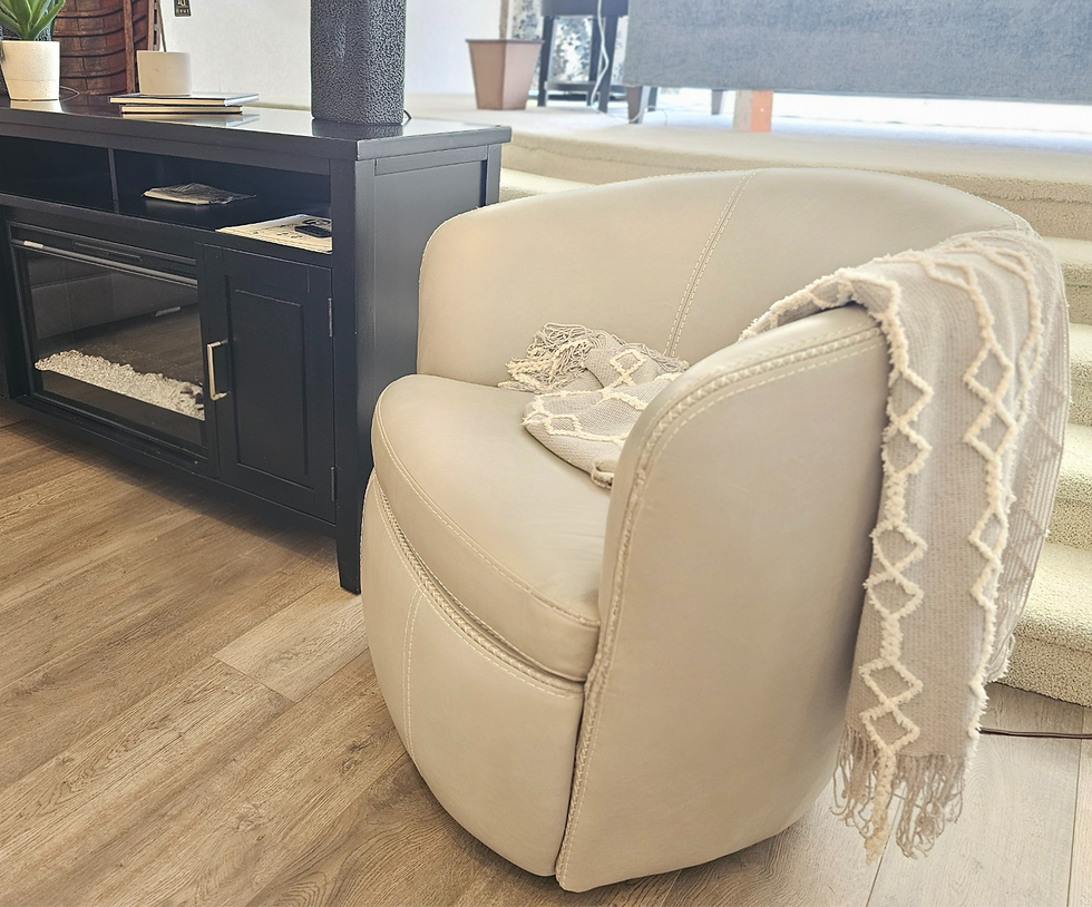 Cream chair with a patterned throw draped over it next to a black cabinet on wooden floor. Stairs and potted plant in the background.