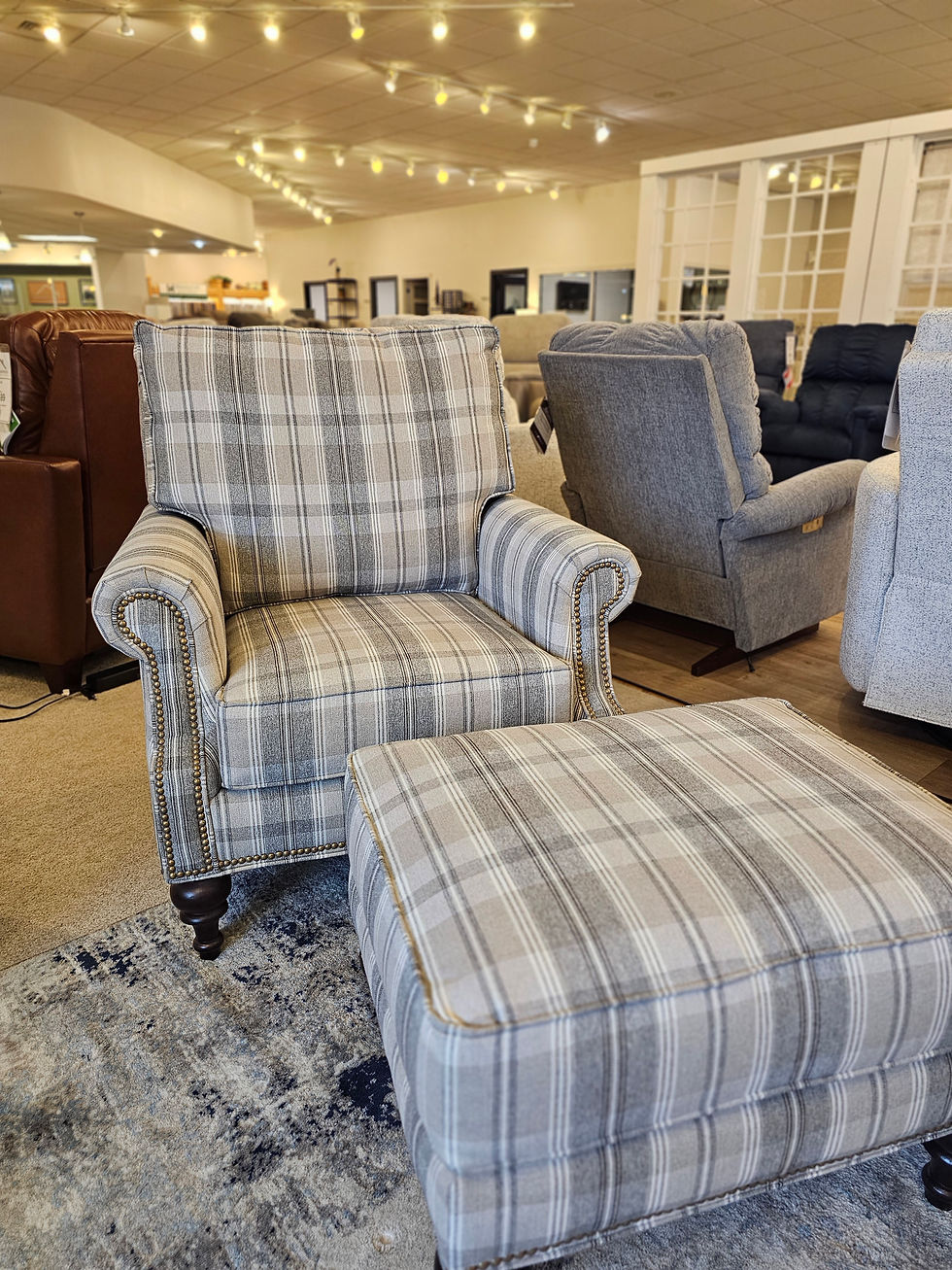 A classic upholstered armchair and matching ottoman with a blue and white plaid pattern, displayed in the Werner Harmsen furniture showroom in Waupun.