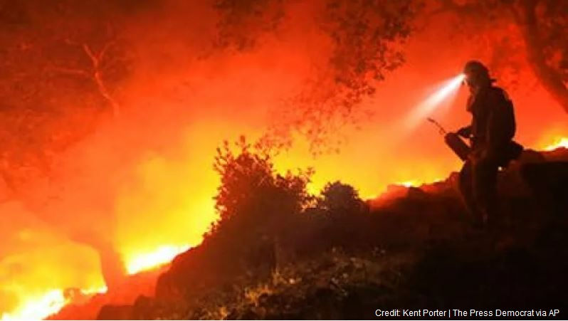 A San Diego Cal firefighter monitors a flare up on the head of a wildfire.