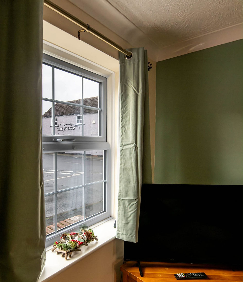 Window with green curtains, and a smart TV in a green room