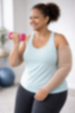 Woman in blue tank top lifts a pink dumbbell, smiling, in a light room with a fitness ball in the background. Positive and active mood.
