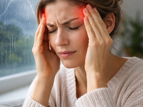 A woman suffers from a headache at home as stormy weather approaches, illustrating how changes in barometric pressure can affect physical health.