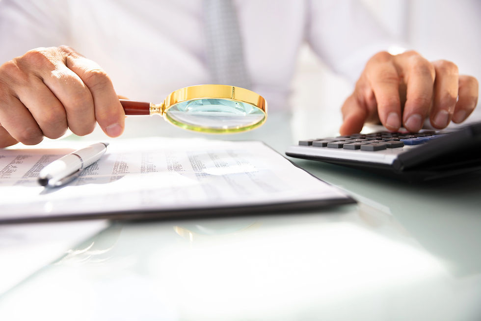 Close-up of hands examining financial documents with magnifying glass and calculator during divorce financial review.