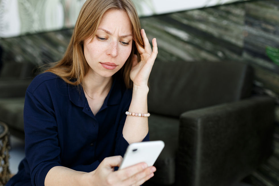 Woman looking at her phone with a concerned expression, contemplating a social media post during divorce.