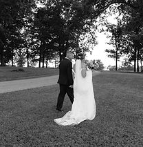 a black and white image of a bride and groom walking hand in hand in at Ritchie Lake, bela