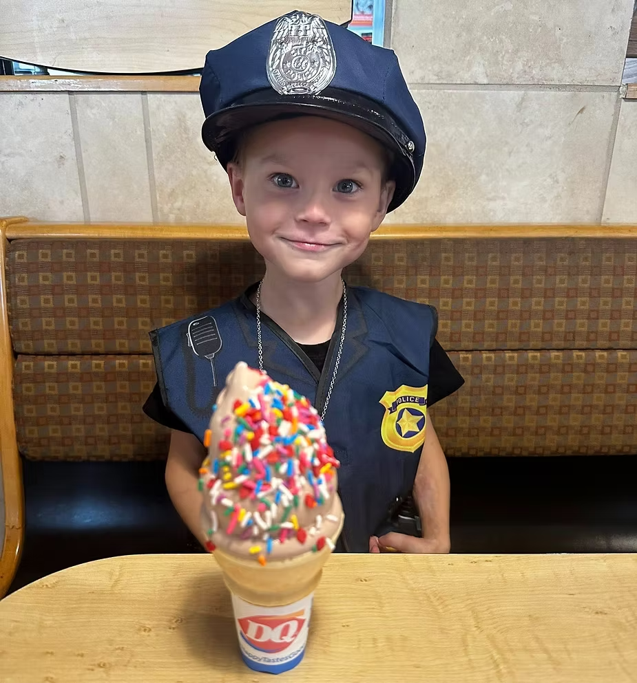 A little officer beams with joy over a colorful DQ ice cream treat.