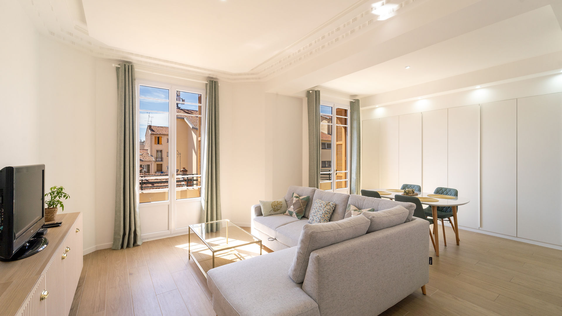 Deux pièces réunies pour un espace de vie de 35m2 avec deux fenêtres. Carrelage façon parquet au sol. Canapé dans les tons de sable et double-rideaux dans les tons tilleul. Création et Maîtrise d'oeuvre Jérôme Caramalli.