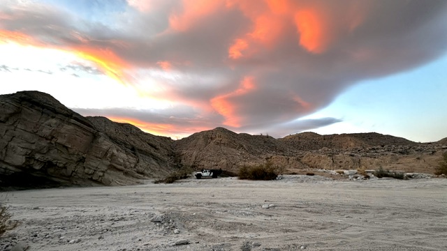 Pink sunset clouds over camp in a desert canyon