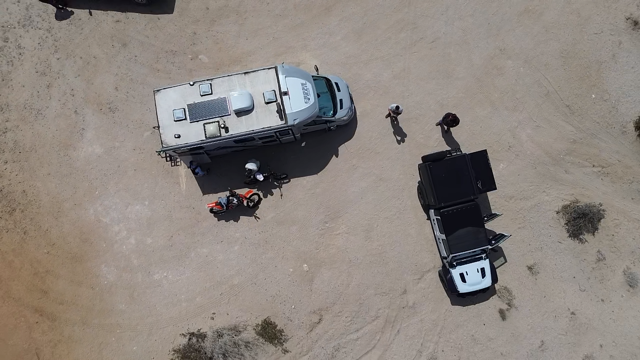 Overhead drone view of camp with a camper van, Jeep and dirt bikes