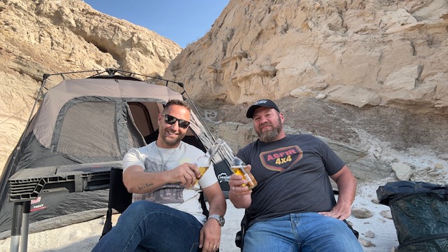 Raising a toast in camp chairs at the foot of a sandstone wall