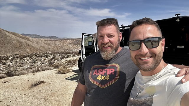 Amir and Arik smiling on the trail beside the Jeep