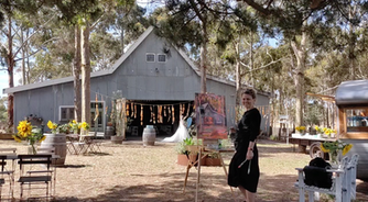 Woman painting near barn, bride in background, sunflowers and outdoor scene. wedding painter rates