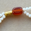 Miniature : Détail du Bracelet Dibili – perles naturelles rouge orangé, agate perse rouge et reflets dorés.