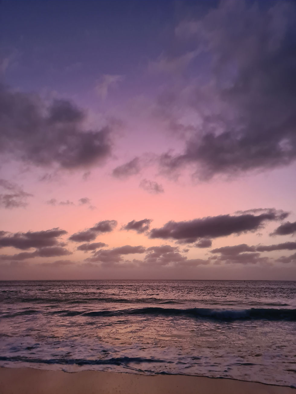 Sunset over ocean with pink and purple sky, dark clouds, and gentle waves on the shore. Serene and tranquil atmosphere. Boa Vista, Cape Verde