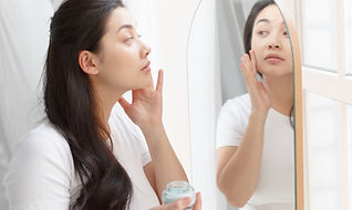 鏡に向かって美容液をつける女性