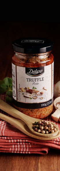 Molho de trufas Delizio, cogumelos, ervas e colheres sobre tecido vermelho.