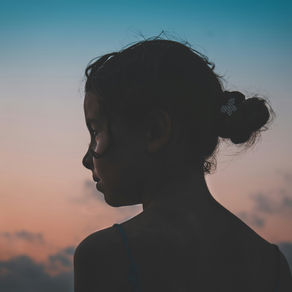Silhouette of a thoughtful young girl against a sunset sky, symbolizing the balance between growth and well-being in education. Encouraging a growth mindset without overwhelming students fosters resilience and lifelong learning.
