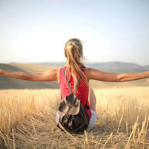 A woman stands in a golden field at sunrise with her arms wide open, symbolising freedom, rest, and release—representing a teacher breaking free from hustle culture and reclaiming her energy.