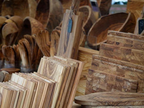 תצוגה של קרשי חיתוך מעץ טבעי במגוון גדלים וצורות בשוק או חנות כלים למטבח.