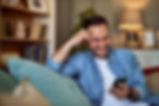 A cheerful young adult man getting a a notification message from his date while sitting an