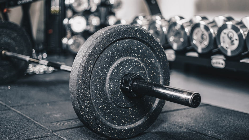 Barbell on the ground surrounded by racked free weights.