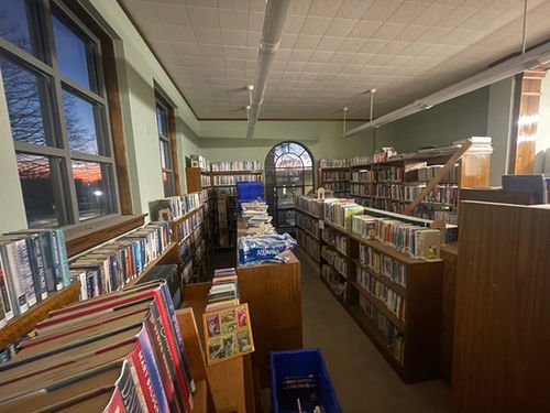Picture of all of the books, shelves, tables, and chairs in the front of the library