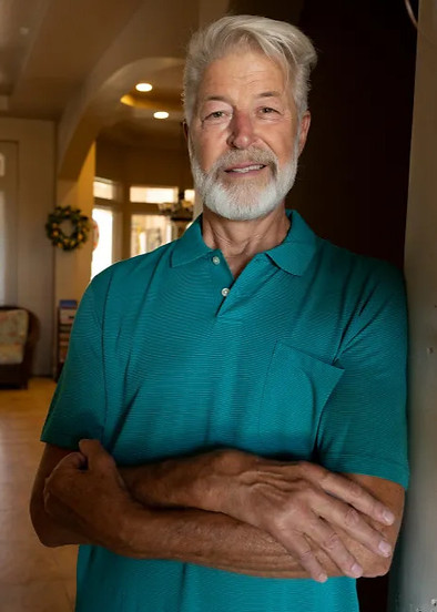 Eldery man smiling with green shirt crossing arms