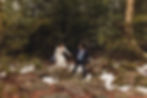 bride and groom walking over snowy rocks by pine trees